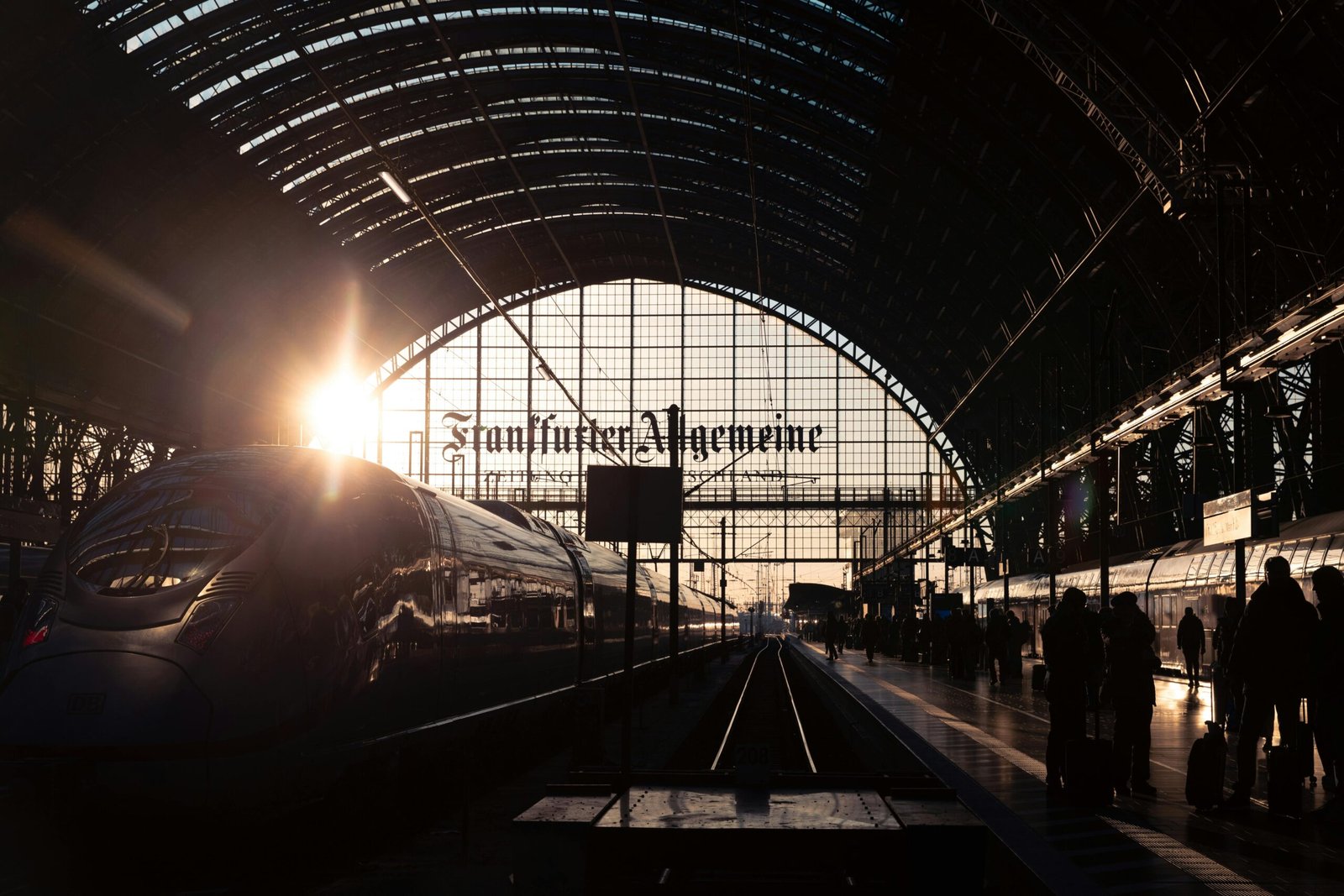 Beautiful sunset at Frankfurt's main train station with travelers and a modern train.